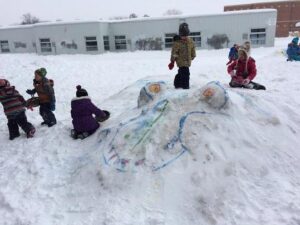 kids on snow pile shaped like a dragon’s head