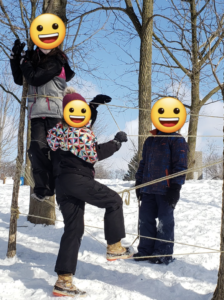 Students climbing a wall made out of rope tied between two trees